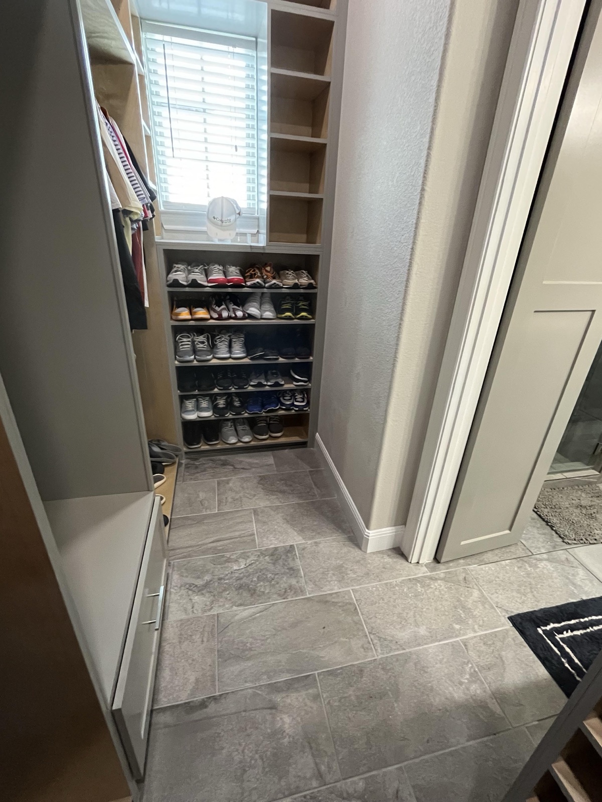 Custom walk-in closet built-in with open shoe shelving and tall storage cabinetry