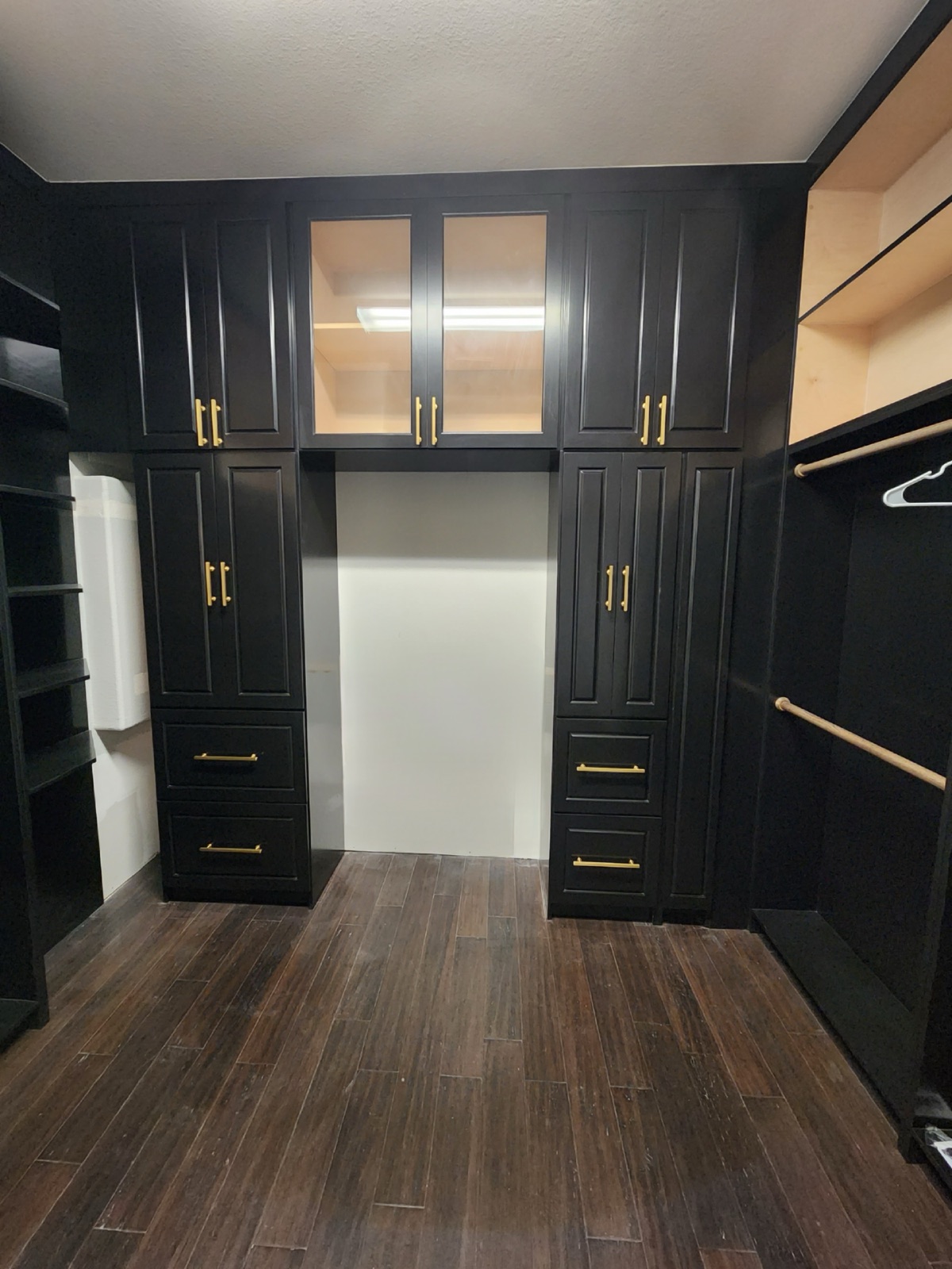 Custom black built-in wardrobe with brass hardware and a glass-front upper cabinet