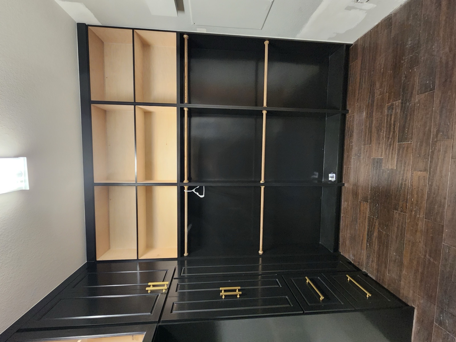 Bespoke black built-in storage wall with open shelving, brass rods, and base drawers