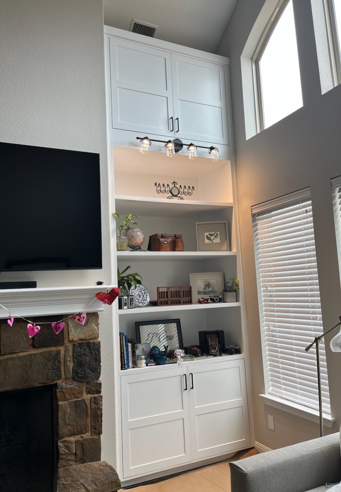 Custom white built-in shelving and cabinetry beside a stone fireplace