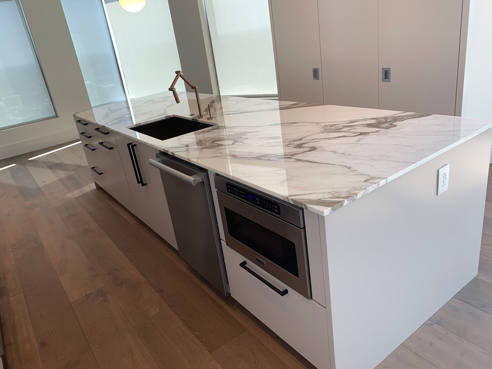 Luxury kitchen with white cabinetry, dark hardware, and stone island