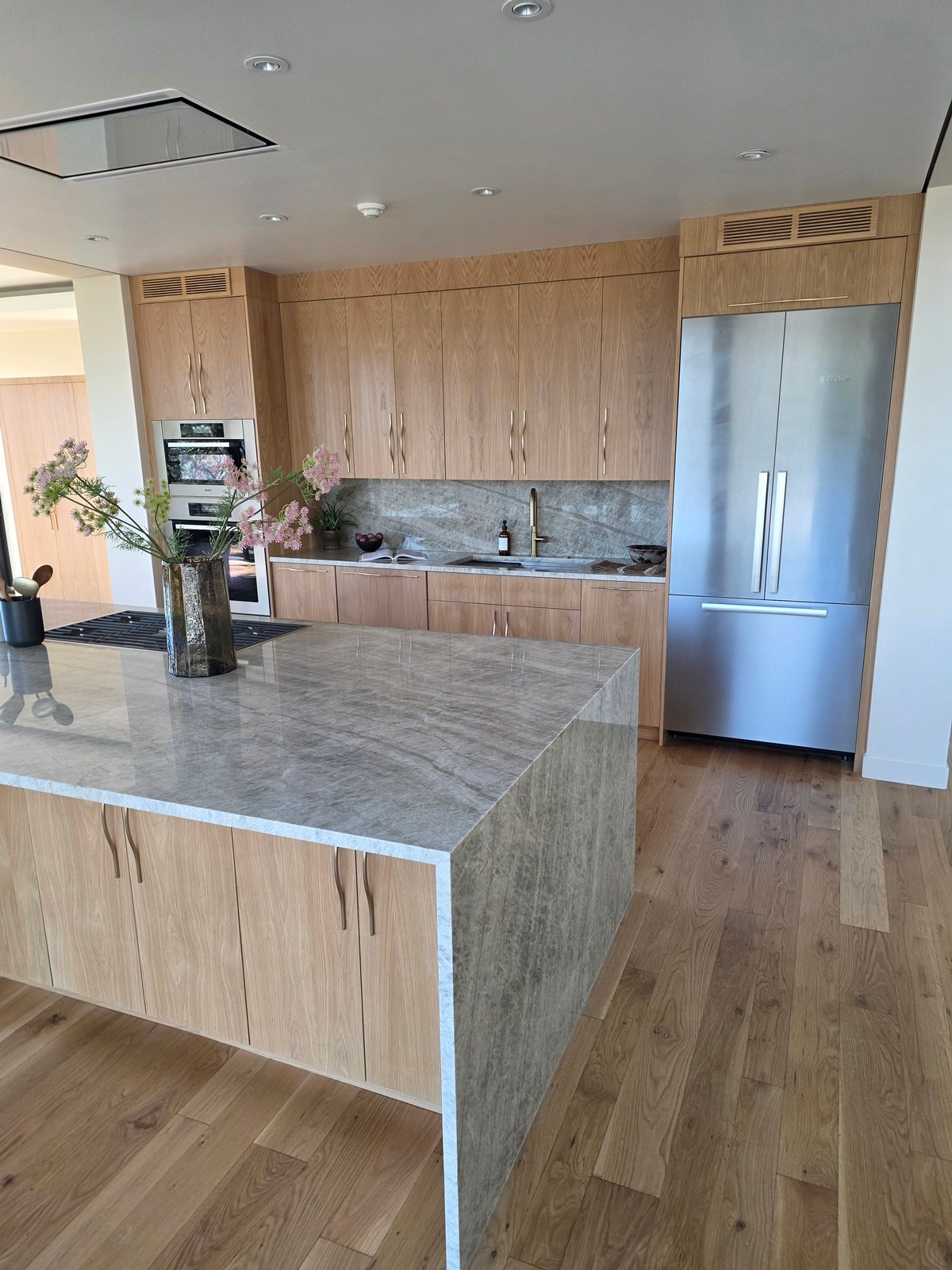 Bespoke kitchen with light wood cabinetry, large island, and stone countertops